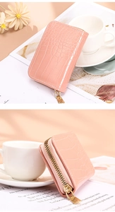 Detailed view of pink crocodile-embossed card holder with premium gold zipper hardware