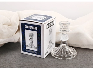 Close-up of glass candle holder in retail packaging on stone textured surface