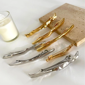 Lava-style metallic geometric hair clips in gold and silver finish on stone props