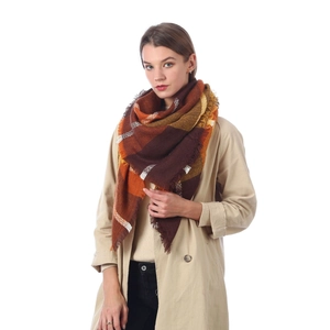 Plaid cashmere-like scarf with orange and brown tassels on a model in a beige coat