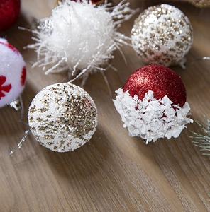 Close-up of Christmas ornaments with glitter, beads, and plush textures on wood
