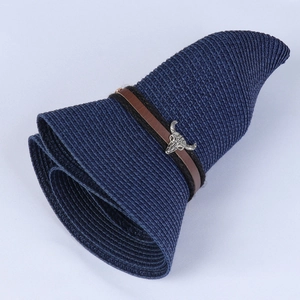 Close-up of navy straw sun hat featuring brown leather band and silver bull head detail