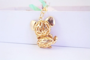Close-up of a golden metal fox keychain with hollow-out design on a gift box background