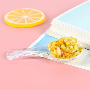 Cuillère miniature en ABS avec faux riz sauté aux œufs sur un fond rose pastel