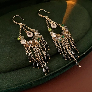 Macro detail of vintage gold-plated tassel earrings with zircon and black beads