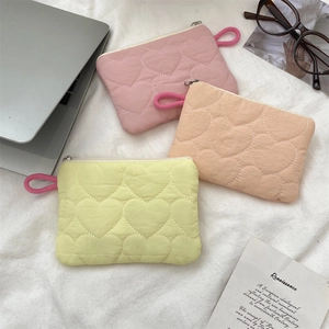 Detailed view of heart-quilted macaron mini bags in pink, orange, and yellow hues