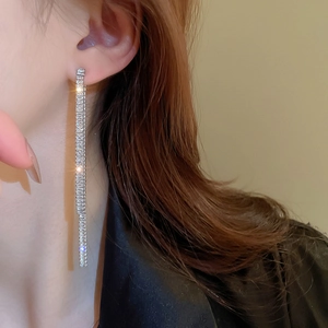 Detail of silver tassel earrings with high-shine zircon crystals worn by a model