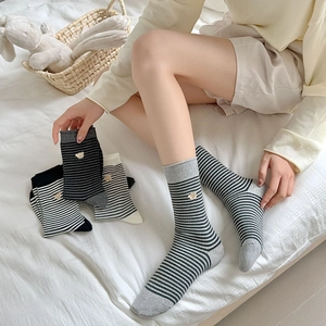 Close-up of striped socks with cute bear embroidery on a soft white bed scene
