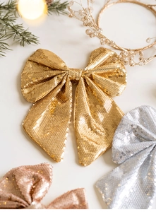 Macro detail of glitter Christmas bows in gold silver and pink with festive pine needles