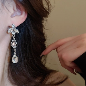 Detailed close-up of sparkling waterdrop tassel earrings with silver rhinestones on model