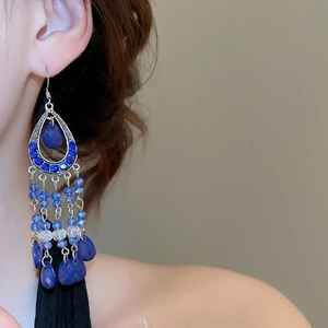 Detailed view of vintage bohemian drop earrings with blue crystal fringe on a model