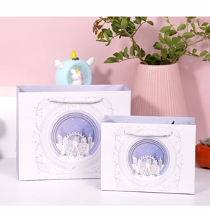 Nahaufnahme der Geschenktüten mit lila Riesenrad und nächtlichen Stadtmotiven