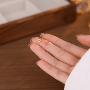 Minimalist S999 sterling silver gold coin stud earrings held on a fingertip