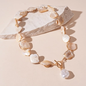 Detail of seashell necklace with gold accents and baroque pearl on OT toggle clasp
