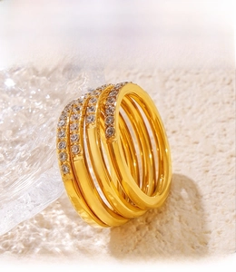 Macro shot of 18K gold plated PVD rings with set cubic zirconia on textured background