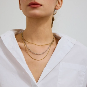 Three-layer stainless steel necklace set with mixed gold and silver chains worn by a model