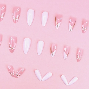 Pink and white almond press-on nails with floral patterns and gold accents