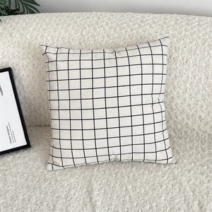 Detailed view of black and white grid cotton linen pillowcase on a soft textured sofa