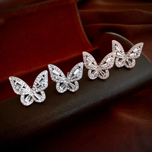 Détails macro des boucles d'oreilles papillon en argent et or rose avec zircons blancs
