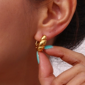 Close-up of elegant 18K gold-plated titanium steel huggie earrings worn by a model