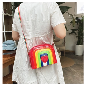 Rainbow striped round crossbody bag featuring a bright red heart detail and woven strap