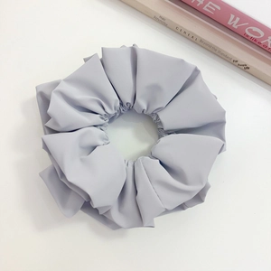 Detail of a large matte lilac faux leather scrunchie with elegant pleated texture