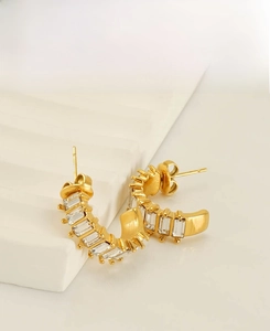 Detail of golden U-shaped stainless steel earrings with rectangular zircon inlay