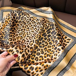 Detail of silk satin scarf with classic leopard print and elegant gold striped borders