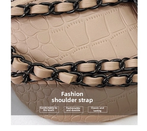 Close-up of beige crocodile pattern leather strap with black metal chain detail