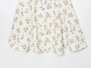 Détail d'une robe en popeline à imprimé fleuri avec fleurs oranges et boutons frontaux