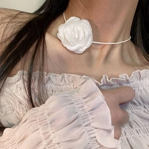Close-up of a white silk rose choker necklace with elegant ribbon ties on a model