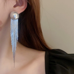 Close-up of long silver fringe earrings featuring a large pearl stud and sleek tassels