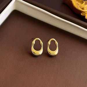 Close-up of golden irregular hollow oval earrings with polished finish in jewelry box