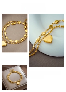 Detail of gold double-layer bracelet featuring heart pendants and LOVE engraving