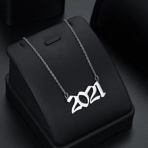 Macro view of silver 2021 year pendant with artistic bold numbers on a black jewelry stand