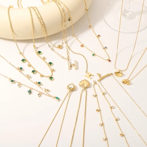 Gold-plated stainless steel necklaces with heart, bamboo, and H-letter charms on white