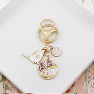 Detailed view of golden enamel charms featuring sakura cat and wisteria moon scene