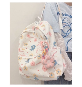 Close-up of white canvas backpack with floral print and pink sunflower plush charm
