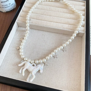 Gros plan d'un collier de perles avec étoiles argentées et pendentif cheval irisé