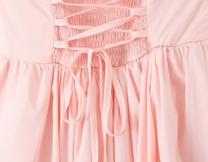 Macro detail of criss-cross tie-back design and elastic ruching on light pink dress
