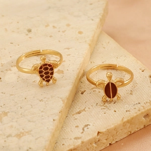 Gros plan détaillé de deux bagues tortue vintage dorées avec motifs rouge-brun sur soie