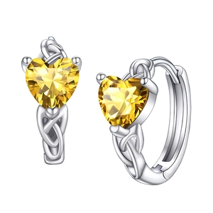 Macro shot of silver heart earrings with yellow stones and Celtic knot texture