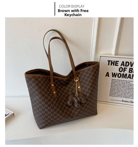 Detalle de bolso tote marrón con monograma MK y un bonito colgante de elefante