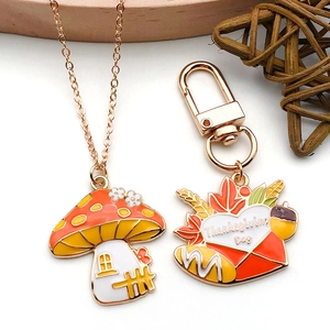 Detail of Thanksgiving mushroom house necklace and letter-engraved enamel keychain charms