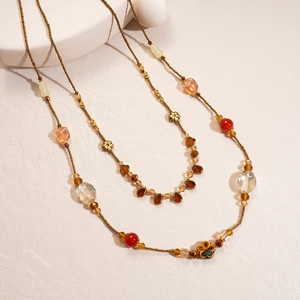 Detail of vintage beaded necklace with amber resin and flower charms on white background