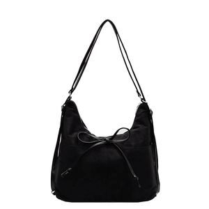 Retro black faux suede shoulder bag for women with elegant bow detail on a white background