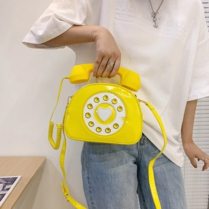 Detail of creative vintage telephone crossbody bag in bright yellow patent leather