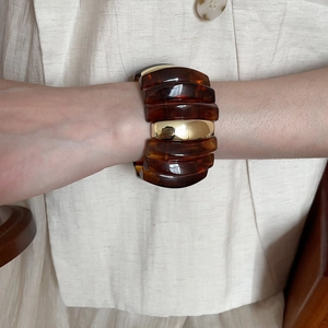 Close-up of chunky amber resin and polished gold metal bracelet on a model wrist