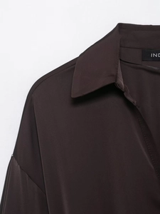 Detail view of smooth chocolate satin shirt fabric with elegant collar and shoulder seams