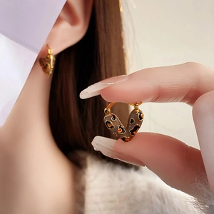 Detailed view of leopard print heart-shaped gold-plated hoop earrings on model and hand